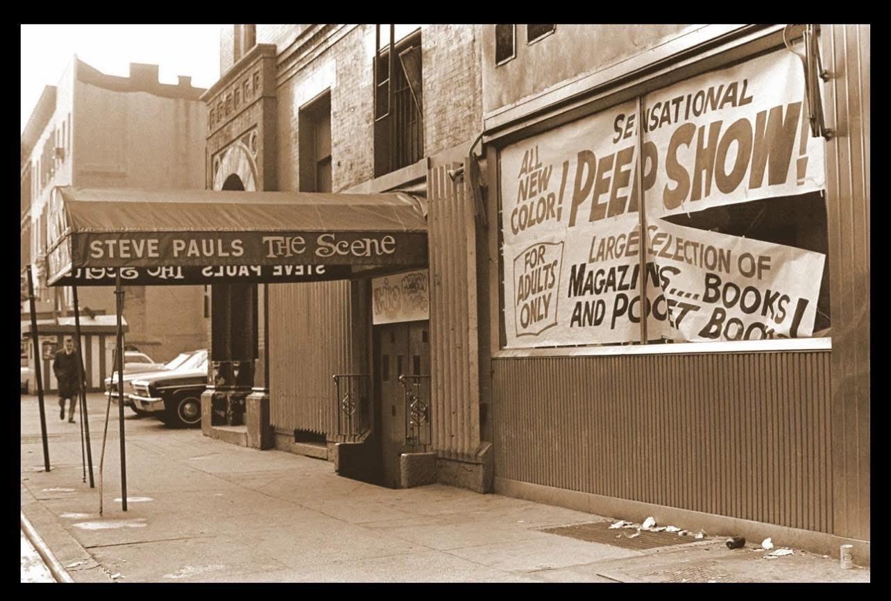 An adult bookstore, called the Sensational Peep Show, in decay, is right next to a swingin' night club called The Scene. 
Andy Warhol did a lot of stuff there. At The Scene, not at the Sensational Peep Show. 
Tho he may have frequented the Sensational Peep Show, as well. I don't know.