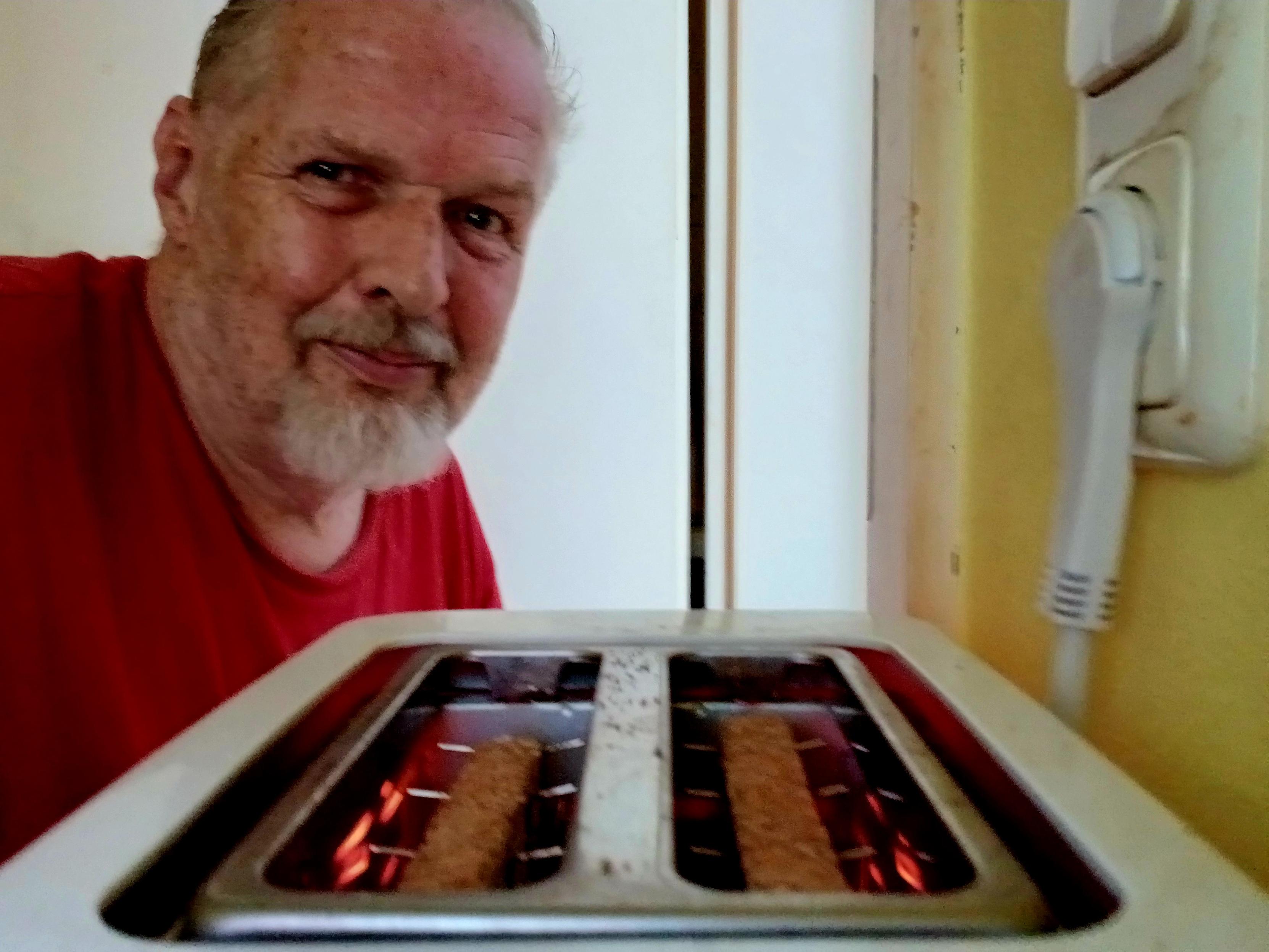 Yours truly, in a red t-shirt, watching filaments glowing red as toast toasts in the toaster, round side down.