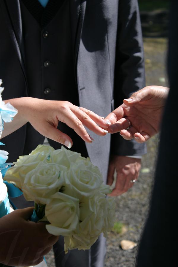 At a wedding, a close-up on the ringed-hand of the bride. She has a white roses bouquet in her right hand that is in the shadow of a guest who lifts delicately her left hand to admire the wedding ring which is illuminated by sunlight. Someone slightly out of focus is facing the camera. We only see his dark costume and his ring which shines under the sunlight too. It is the happy husband. 
––––––
Shot with Canon 300D + EFS 18‑55mm f/3.5‑5.6 IS2 on August 2016. 
55mm – 1/800s – f/6,3 – ISO 200