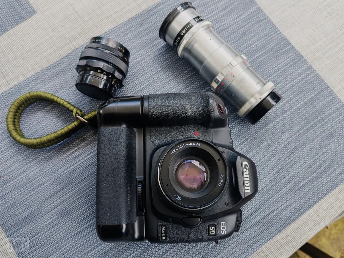 A digital camera Canon 5DMKII with old vintage lenses attached or waiting to be used.