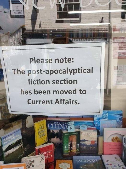 Aparador d'una llibreria amb un cartell que diu: 'Please note: The post-apocalyptical fiction section has been moved to Current Affairs'. A sota hi ha